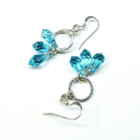 The Sterling Silver Hammered Aqua Crystal Cascading Drop Earrings by Alexa Martha Designs feature three faceted blue crystals on each earring, accented with textured silver rings and finished with fishhook ear wires.