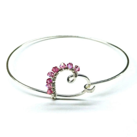 The Alexa Martha Designs Wire Wrapped Pink Crystal Heart Bangle features a heart-shaped centerpiece and sparkling pink crystals for an artisan touch.