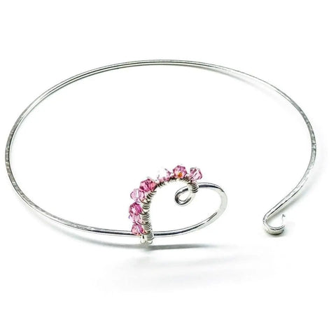 The Alexa Martha Designs Wire Wrapped Pink Crystal Heart Bangle features a sterling silver heart, delicately wire-wrapped and accented with sparkling pink crystals for a romantic look.