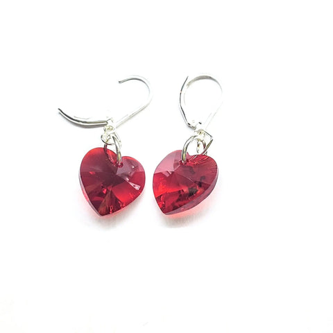 The Sterling Silver Red Heart Crystal I Love You Jesus Earrings by Alexa Martha Designs feature faceted red Swarovski heart pendants on silver hooks, shown on a white background—ideal for fans of elegant sterling silver heart earrings.