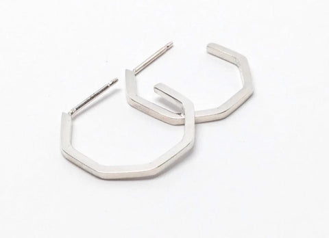The SILVER GEO HOOPS | SMALL by Sarah Cecelia are handmade in the USA. These sterling silver earrings feature a shiny, geometric hexagonal design and are shown on a plain white background.