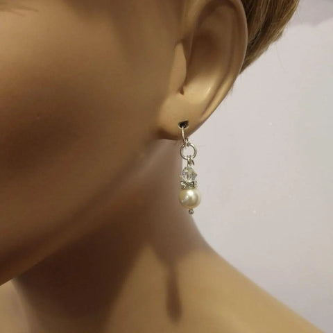 A mannequin’s ear displays Alexa Martha Designs Silver Swarovski Crystal Pearl Stack Earrings in various colors, featuring a clear bead above a white pearl, all linked by silver components.
