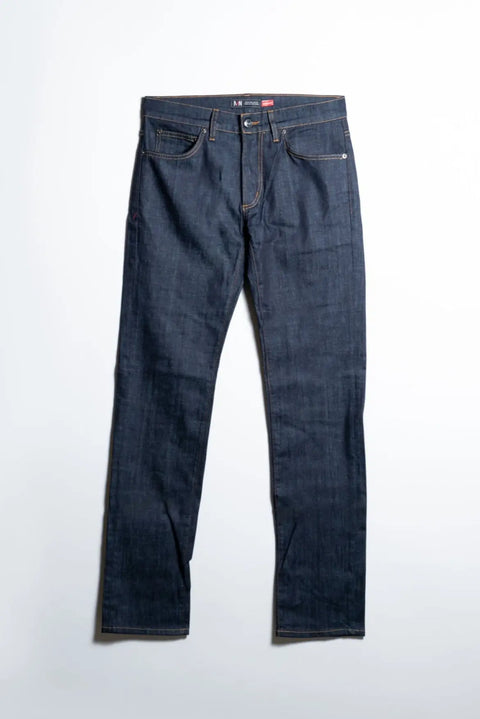 The Nelson Dark Wash Denim by Marc Nelson is a pair of dark blue 5-pocket jeans with orange stitching, front pockets, belt loops, and a classic zipper fly, shown laid flat on a white surface.