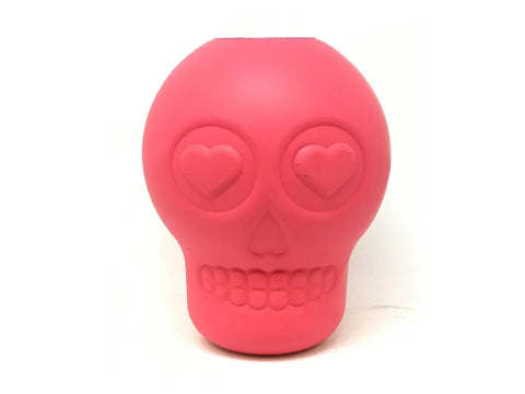 The SodaPup Sugar Skull EDispenser is a durable pink rubber chew toy and treat dispenser with heart-shaped eyes and a smiling mouth, ideal for playful dogs. Shown on a plain white background.