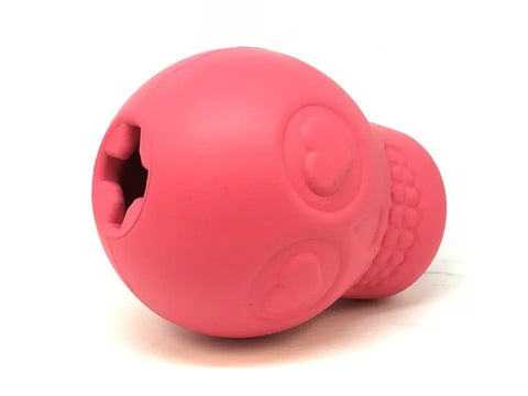 The SodaPup Sugar Skull EDispenser is a pink, durable rubber dog toy with heart-shaped eyes and an open mouth treat dispenser. Its round, textured skull design makes it a fun chew toy and interactive treat dispenser for dogs.