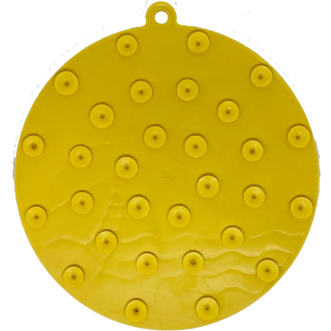 The SodaPup Sun N Sea EMat Enrichment Lick Mat features a round, flat yellow design with raised bumps, a wavy pattern for spreading treats, suction cups for stability, and a small hanging loop—perfect for dog enrichment.