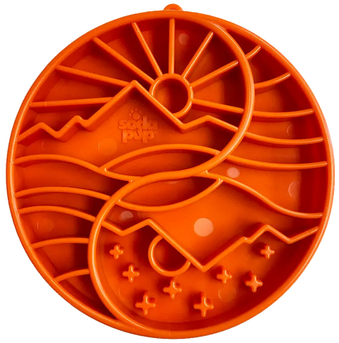 The SodaPup Sun and Moon Design ETray is a round, orange silicone slow feeder tray for dogs, featuring raised mountain, sun, and wave patterns in two yin-yang sections. SodaPup is embossed at the center. Ideal for small dogs’ enrichment.