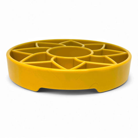 The SodaPup Sunflower Design ETray Enrichment Shallow Slow Feeder Dog Bowl features a yellow, round structure with wedge-shaped compartments radiating from a central circle, designed to slow feeding. Set against a plain white background.