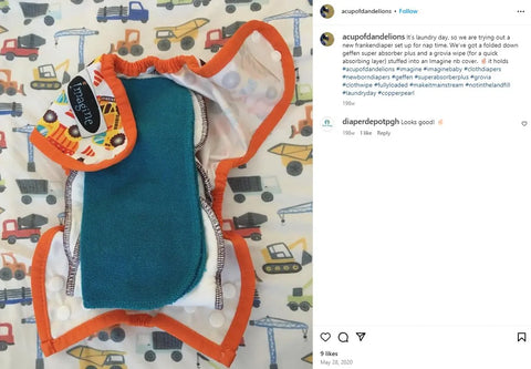 A Geffenbaby Super Absorbers Plus cloth diaper insert with teal absorbency and orange trim is laid open on a colorful construction-themed background, featuring a round “Imagine” tag—ideal for eco-conscious families.