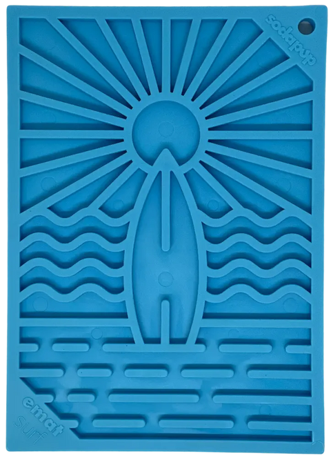 The Surfs Up Design EMat Enrichment Lick Mat - Small by SodaPup features a blue silicone surfboard, sun rays, and ocean waves. Perfect for canine enrichment and foraging. SodaPup and Emat Surf are displayed in the corners.
