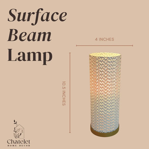 The Surface Beam Lamp by Chatelet Manufacturing is a 10.5” tall, 4” wide cylindrical table lamp with a textured surface, casting warm ambient, color-changing light through patterned holes—ideal for nightstands or coffee tables.