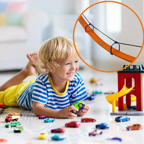 A young child with blonde hair and a striped shirt smiles on the floor, playing with colorful cars. An inset highlights the Chatelet Manufacturing Suspension Bridge Kit Compatible With Hot Wheels Racetracks on the track.