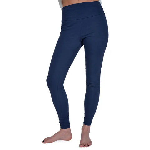 A person models Spiritex | Sustainable Apparel Yoga Leggings, high-waisted and dark blue, standing barefoot on a white background with only their lower half visible.