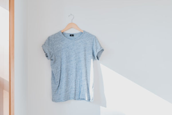 Gray t-shirt on a hanger against a white wall