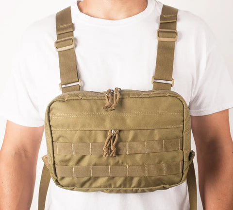 A person wearing a white t-shirt models the MIS Chest Rig - Coyote Tan, made from water-resistant Cordura Nylon with adjustable straps, zippered compartments, and PALS webbing for organized gear carrying.