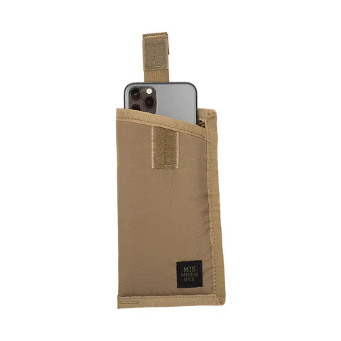 The MIS Tactical Key Strap Set in Coyote Tan is a water-resistant fabric pouch with durable MIL-SPEC nylon webbing, Velcro strap, and a black “MIS Made in USA” label. Shown partially holding a smartphone on a white background.