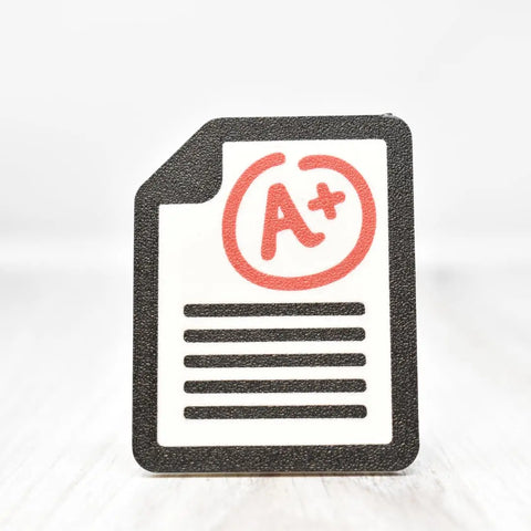 The FRESHe Baglets Teacher Charm by Chatelet Manufacturing features a paper icon with black text lines and a bold red A+ at the top—perfect as a decorative tote bag charm for teachers. Compatible with Bogg Bags, Simply Southern, and more.