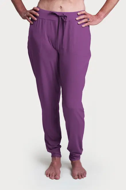 A person models purple Goodnighties Jogger Pants, barefoot with hands on hips, against a white background.