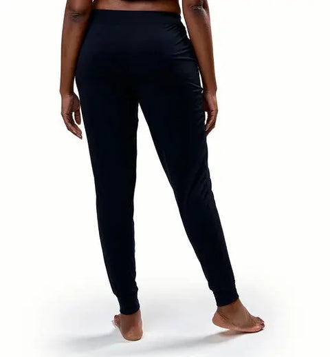 A person stands barefoot on a white background, shown from the back with one leg slightly bent, wearing Goodnighties Jogger Pants.