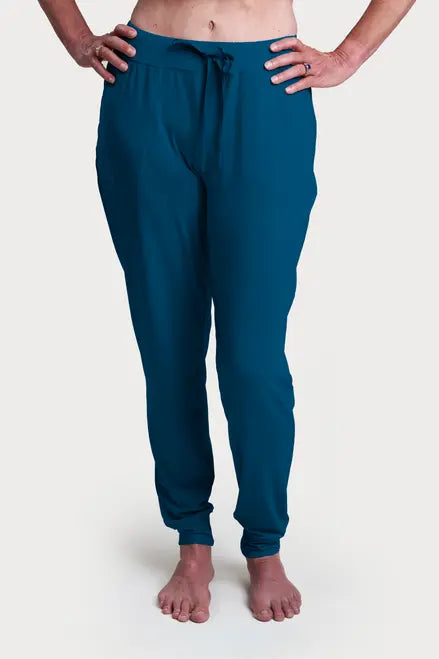 A person stands barefoot on a white background, wearing Goodnighties Jogger Pants in teal with front pockets and a drawstring waist. Crafted in the USA, these joggers offer both comfort and style.