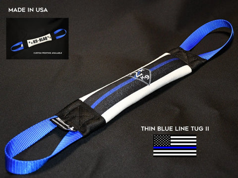 A Thin Blue Line 2 Fire Hose Training Tug - Flag Series by Bulletproof Pet Products Inc is shown in black, white, and blue with blue handles on a black background. Text says Made in the USA and highlights custom printing and Thin Blue Line flag.
