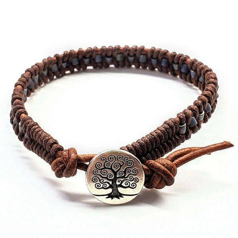 The Alexa Martha Designs Tree of Life Button Brown Gray Leather Wrap Seed Bead Bracelet features a braided leather band and an engraved tree of life charm, shown against a plain white background.