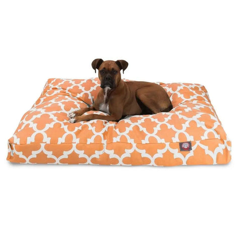 A brown dog with a white chest lies on the Majestic Pet Trellis Rectangle Dog Bed, which has an orange and white pattern and a washable cover, set against a plain white background.