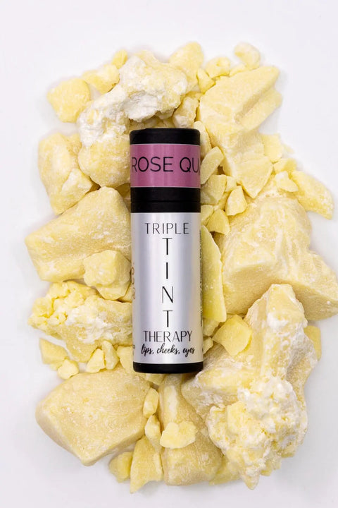Cheryl Kelly & Co. Triple Tint Therapy – Lip, Cheek & Eye Color in Rose Quartz sits on chunky yellow shea butter pieces, set against a white background with eco-friendly packaging.