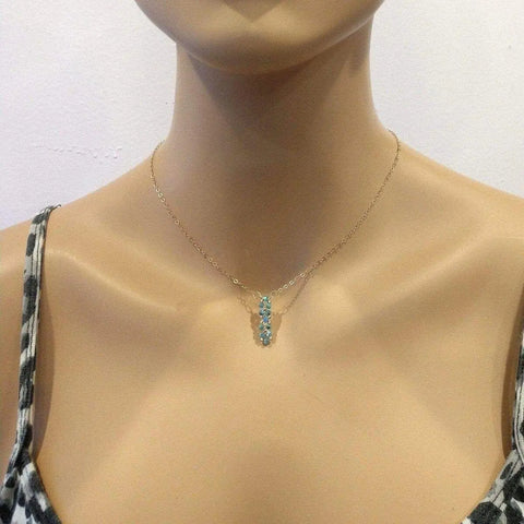 A mannequin models Alexa Martha Designs Tiny Super Sparkly Rock Candy Crystal Bar Necklace—a delicate, handmade piece with a vertical cluster of light blue stones—paired with a black and white patterned top.