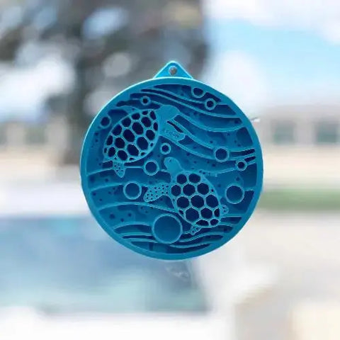 A blue circular ornament featuring two sea turtles amid waves and bubbles resembles the calming patterns of the SodaPup Turtle Emat-Mini Enrichment Lick Mat With Suction Cups.
