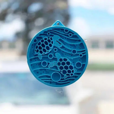 A blue circular ornament featuring two sea turtles amid waves and bubbles resembles the calming patterns of the SodaPup Turtle Emat-Mini Enrichment Lick Mat With Suction Cups.