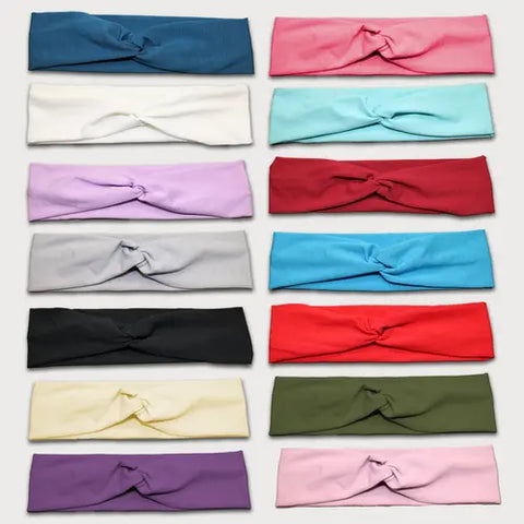 A display of fifteen Goodnighties Twist Headbands in soft, lightweight solid colors—blue, pink, mint, and more—arranged in three vertical columns. Each American-made accessory adds a stylish pop to any look.
