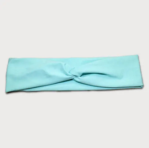 The Goodnighties Twist Headband is a soft, lightweight American-made hair accessory in light blue with a central knot design, shown flat on a plain white background.