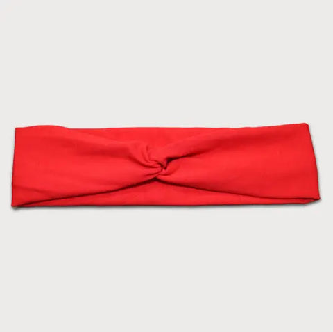 The Goodnighties Twist Headband is a soft, lightweight red fabric headband with a simple center knot, shown laid flat on a light gray background.