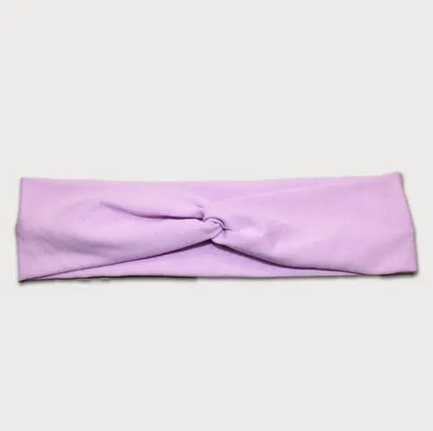 The Goodnighties Twist Headband is a soft, lightweight accessory in light purple featuring a center twisted knot, shown laid flat on a white background.