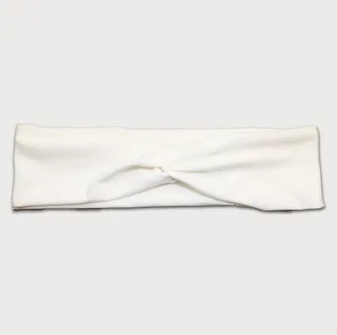 The Goodnighties Twist Headband is a soft, lightweight white hair accessory with a center knot design, made in the USA. Shown on a minimal light background.