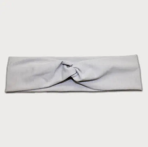 The Goodnighties Twist Headband features a soft, lightweight light gray fabric with a central knot design, shown laid flat on a white background.