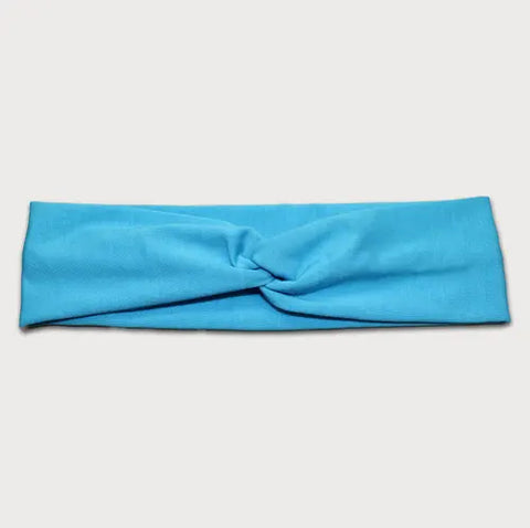 The Goodnighties Twist Headband is a soft, lightweight accessory in light blue with a subtle center twist knot, shown laid flat on a white background.