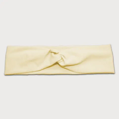 The Goodnighties Twist Headband is a soft, lightweight hair accessory in light yellow with a central knot design, made in the USA. Shown on a plain white background.