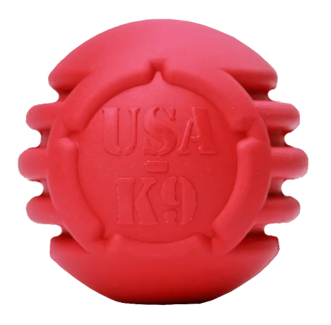 The SodaPup USA-K9 Stars and Stripes Ultra-Durable Rubber Chew Ball is a red, round toy with ridged sides and embossed branding, designed for power chewers and perfect as a dental dog toy.