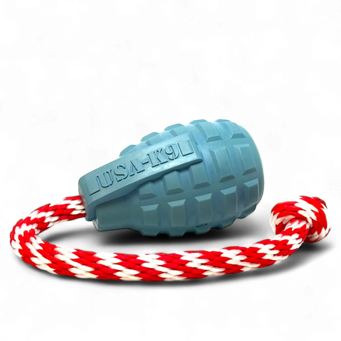 The SodaPup USA-K9 Grenade Durable Rubber Chew Toy in steel blue, attached to a red and white braided rope, is shown against a solid black background. This versatile toy also works as a treat dispenser, tug toy, reward toy, and retrieving toy.