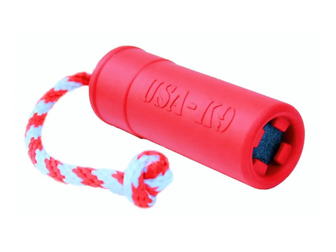 The SodaPup USA-K9 Firecracker Durable Rubber Floating Training Dummy - Large - Red is a cylindrical dog toy with USA-K9 embossed, a braided red, white, and blue rope handle, a black end piece, and is veterinarian approved.
