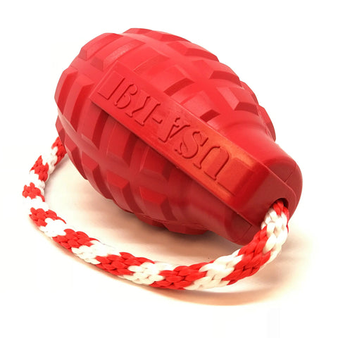 The SodaPup USA-K9 Grenade Durable Rubber Chew Toy is a red, grenade-shaped toy with a textured surface and red-and-white braided rope handle. It dispenses treats and works as a reward, tug, and retrieving toy. USA-K9 logo embossed on the side.