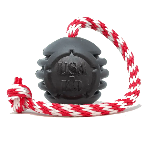 The SodaPup USA-K9 Magnum Black Stars and Stripes is an ultra-durable rubber chew, reward, tug, and retrieving toy for power chewers—made in the USA and attached to a red, white, and gray braided rope loop.