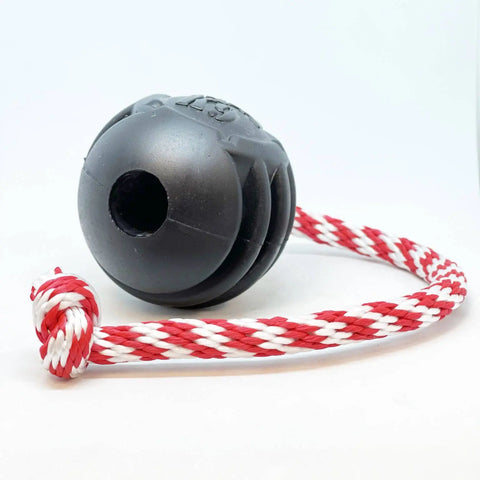 The SodaPup USA-K9 Magnum Black Stars and Stripes Ultra-Durable Rubber Chew Toy features a grooved rubber ball with a hole, attached to a thick braided red-and-white rope—ideal for power chewers who love tug, fetch, and tough play.