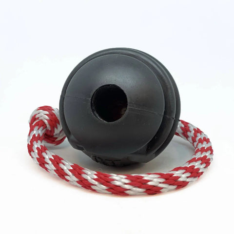 The SodaPup USA-K9 Magnum Black Stars and Stripes Ultra-Durable Rubber Chew Toy is a black dog ball with a center hole, attached to a red and white braided rope, coiled on a white background.