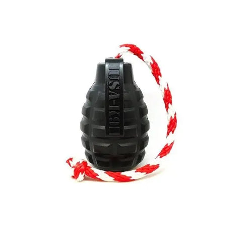 The SodaPup USA-K9 Magnum Grenade, a black, grenade-shaped durable chew and reward toy, is attached to a red and white braided rope and displayed against a white background.