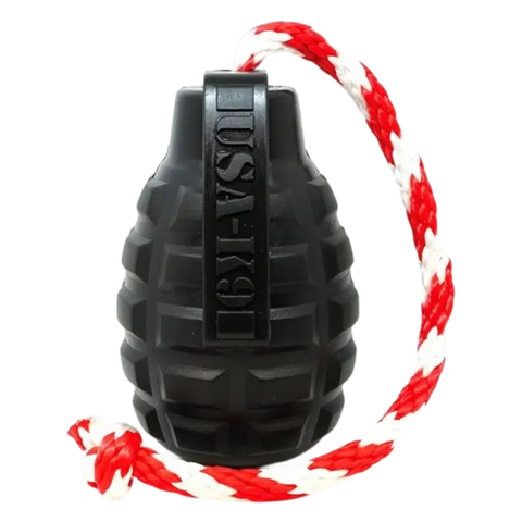 The SodaPup USA-K9 Magnum Grenade is a black, durable rubber dog toy with a textured surface and treat dispenser, made in the USA, attached to a red-and-white braided rope.