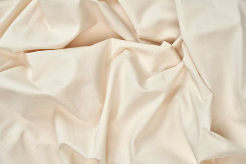 The Cotton Percale Bed Sheet Set by American Blossom Linens features a textured, natural look with visible folds and specks. Crafted from luxurious, USA-grown cotton fibers, these cream-colored sheets offer added comfort and quality.
