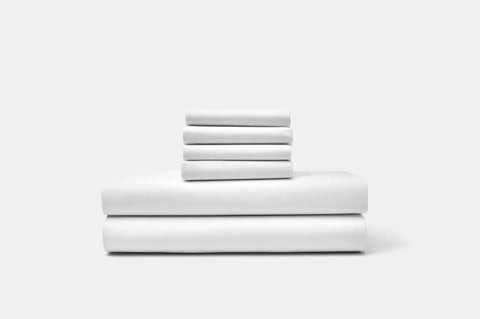 Neatly folded, the American Blossom Linens Cotton Percale Bed Sheet Set—crafted from USA-grown cotton—is stacked in two piles against a plain white background.